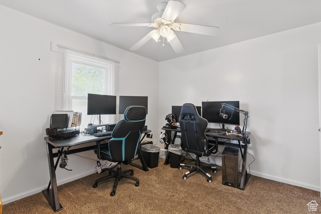 Carpeted office space with a ceiling fan and baseboards