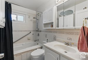 Full bath with tiled shower / bath combo, vanity, and toilet