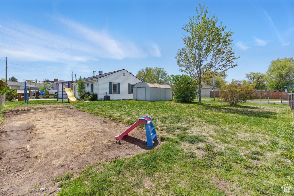 View of yard featuring fence, an outbuilding, a shed, and a playground