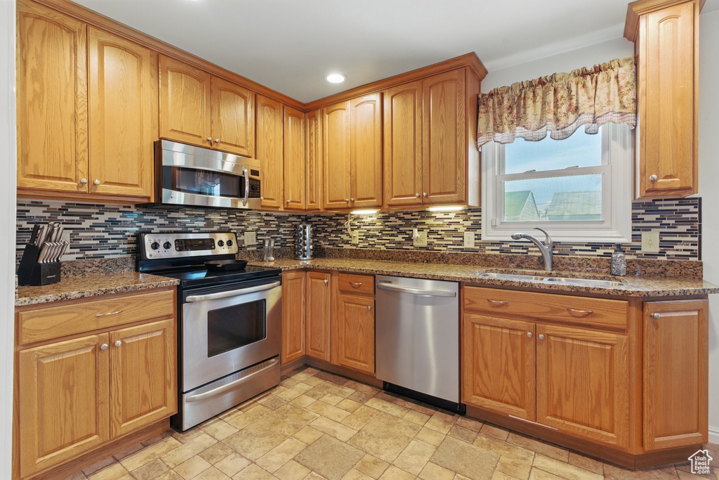 Kitchen with tasteful backsplash, stainless steel appliances, dark stone counters, and a sink