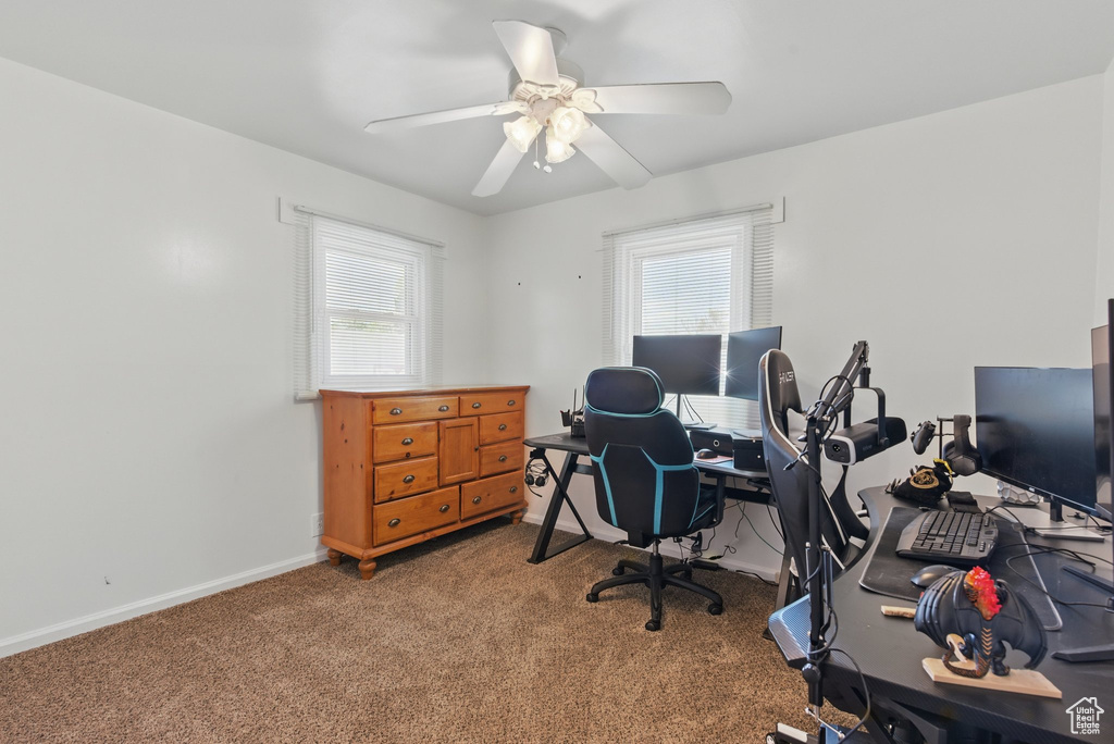Carpeted office space featuring baseboards and a ceiling fan