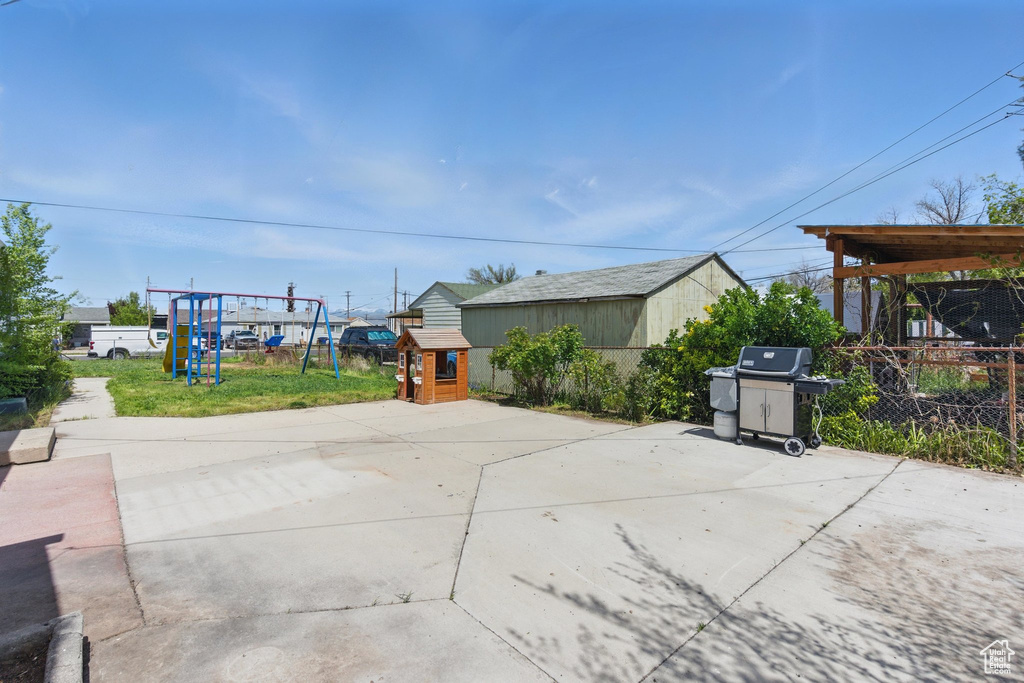 View of patio / terrace with a storage unit, fence, an outbuilding, area for grilling, and a playground