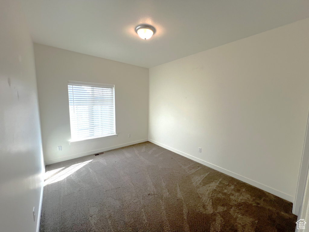 Carpeted spare room featuring baseboards and visible vents