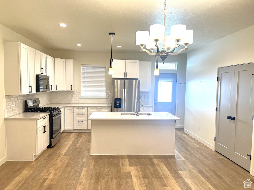 Kitchen with a sink, light countertops, a chandelier, stainless steel appliances, and recessed lighting