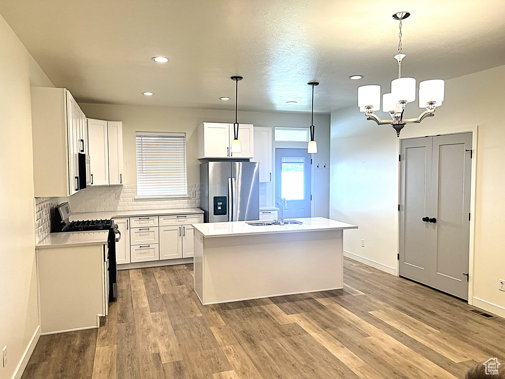 Kitchen featuring a sink, light countertops, stainless steel appliances, white cabinetry, and backsplash