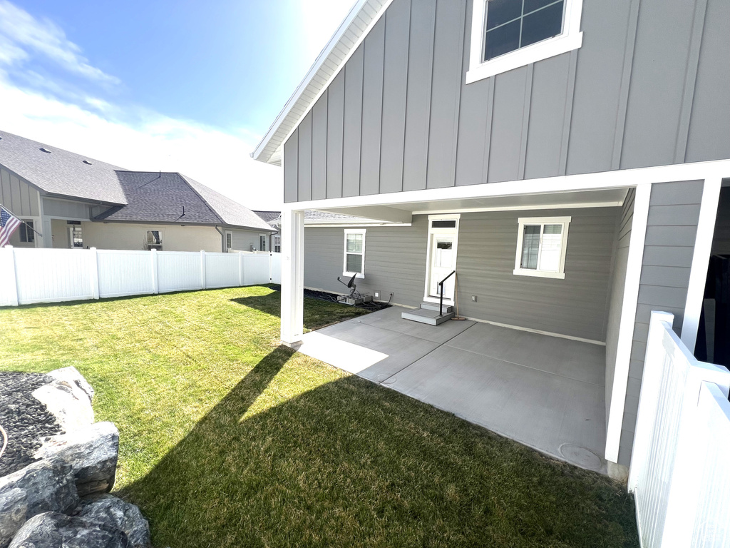 Rear view of house featuring board and batten siding, fence, a yard, and entry steps