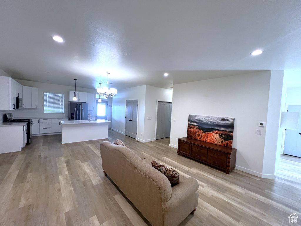 Living room featuring an inviting chandelier, recessed lighting, light wood finished floors, and baseboards