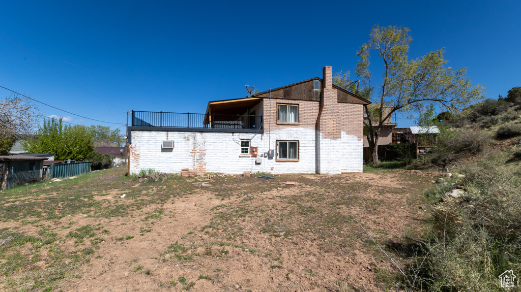 Back of property with brick siding, a balcony, and a chimney