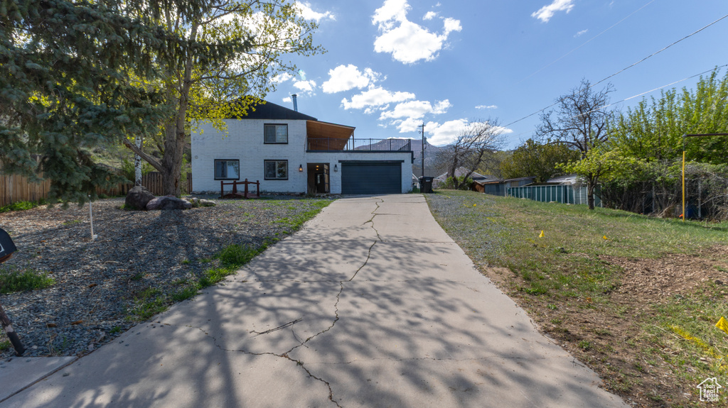 View of front of home with a garage, fence, and aphalt driveway