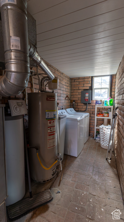 Interior space featuring laundry area, independent washer and dryer, brick wall, water heater, and brick floor