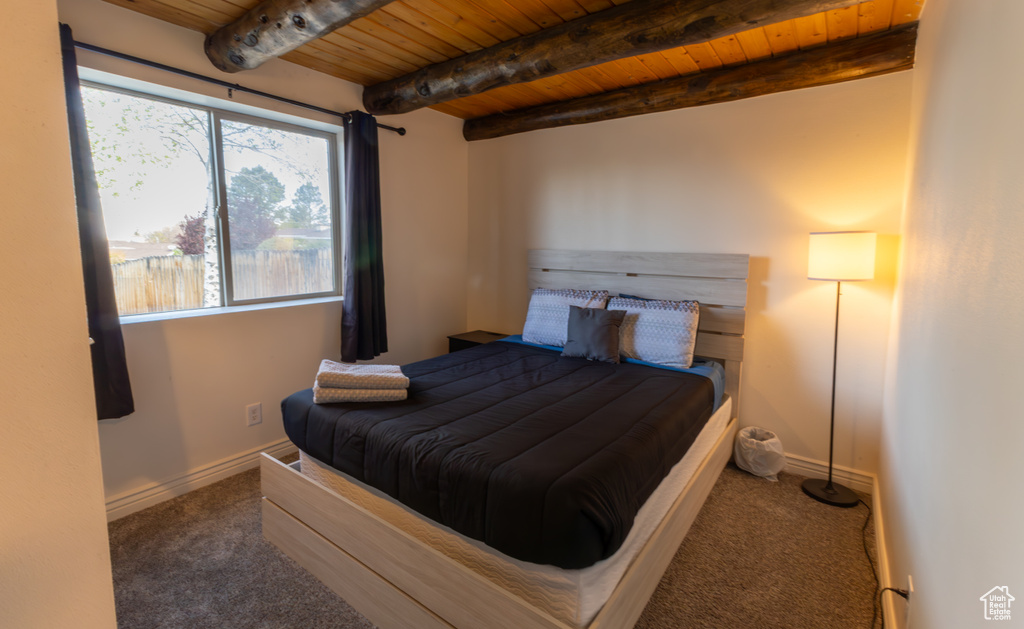 Bedroom with carpet floors, beamed ceiling, baseboards, and wood ceiling