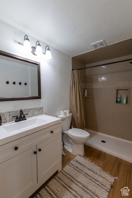 Bathroom featuring visible vents, vanity, wood finished floors, curtained shower, and toilet