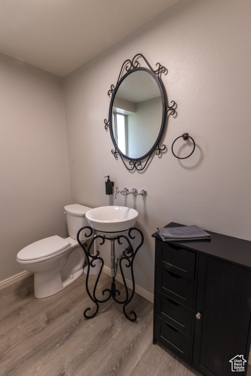 Bathroom with baseboards, a sink, wood finished floors, and toilet