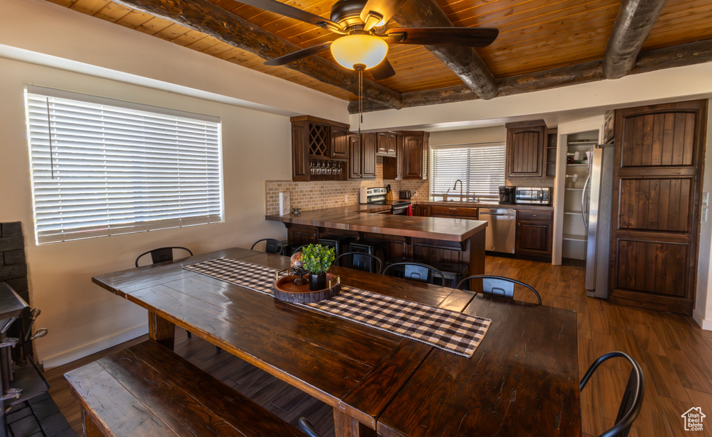 Dining space featuring ceiling fan, beam ceiling, wood-type flooring, baseboards, and wooden ceiling