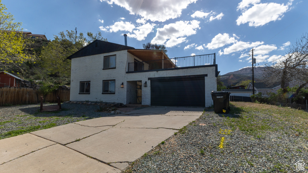 Modern home featuring a garage, a balcony, fence, and driveway