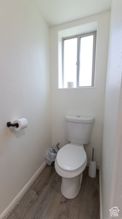 Bathroom featuring baseboards, toilet, and wood finished floors