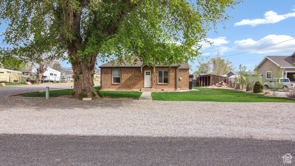 Bungalow-style home featuring brick siding, a residential view, and a front yard