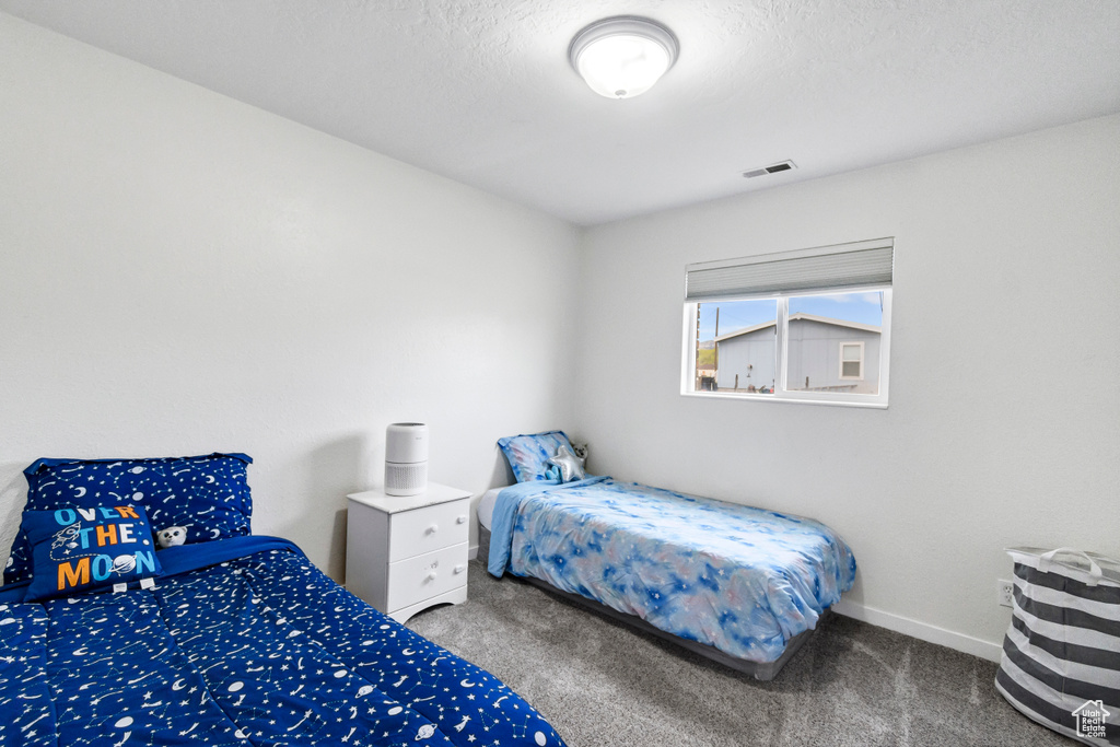 Carpeted bedroom with baseboards and visible vents