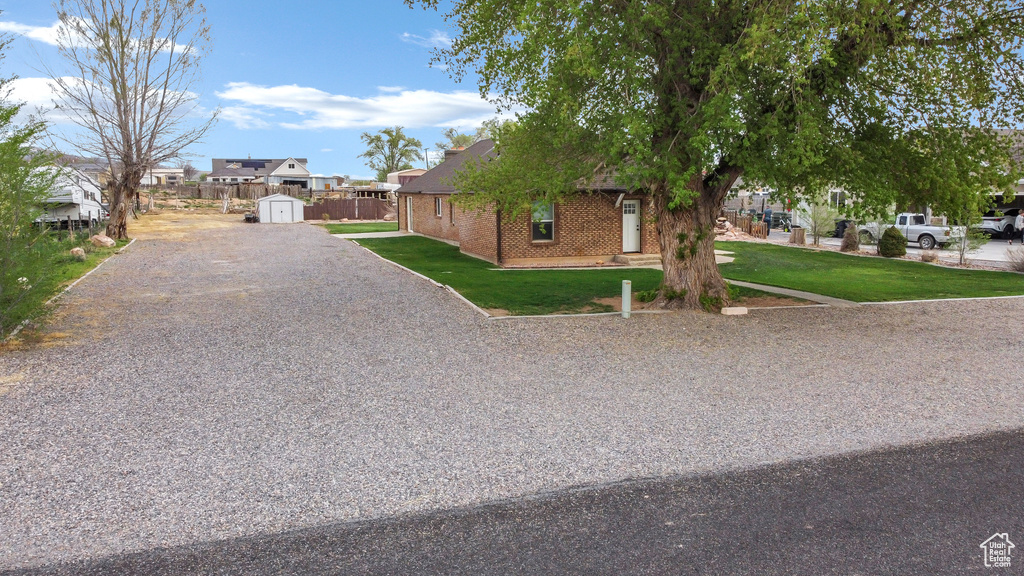 View of front of home with a front yard, driveway, a storage unit, an outbuilding, and a residential view