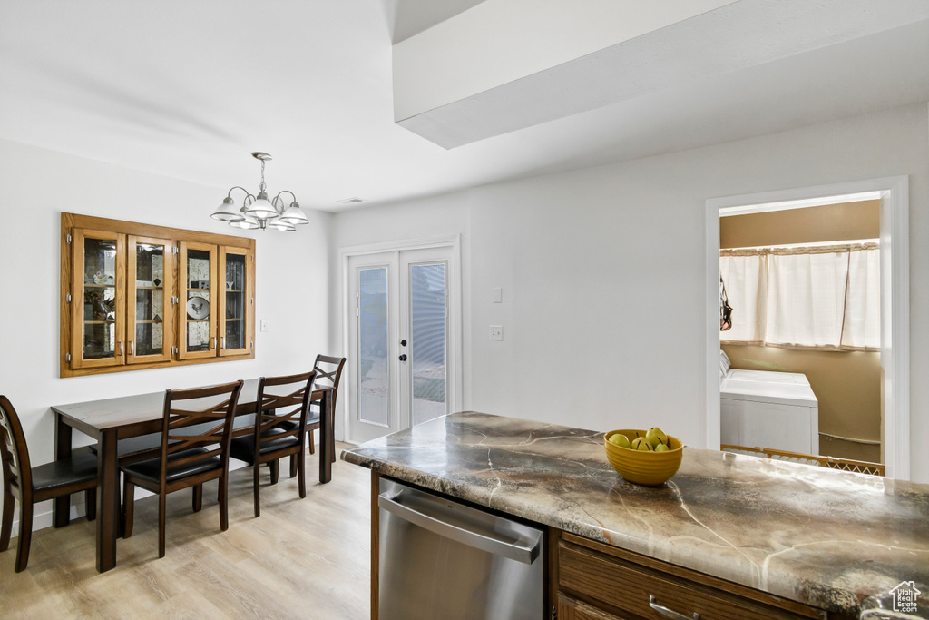 Kitchen with stainless steel dishwasher, pendant lighting, light wood-type flooring, washer and clothes dryer, and a notable chandelier