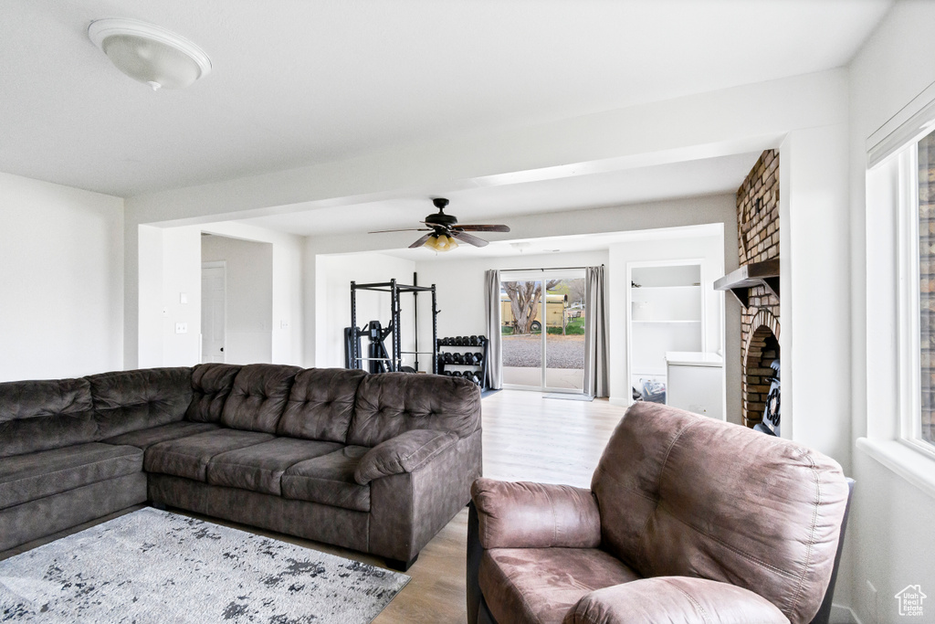 Living area with ceiling fan, a large fireplace, a healthy amount of sunlight, and light wood-style floors