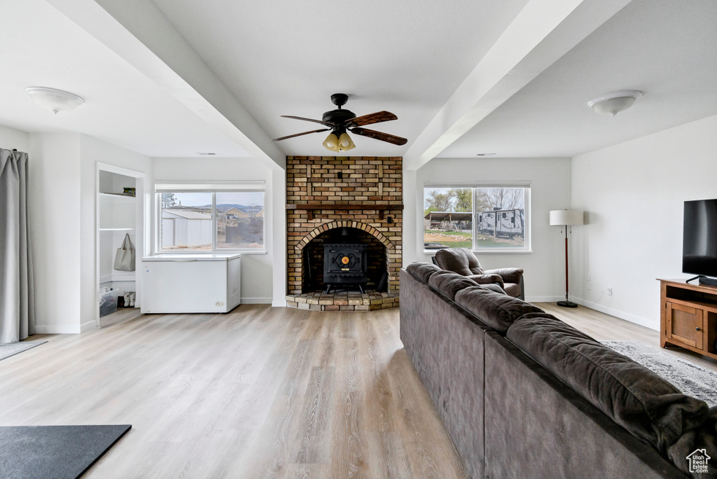 Living area with baseboards, a ceiling fan, light wood finished floors, and a wood stove