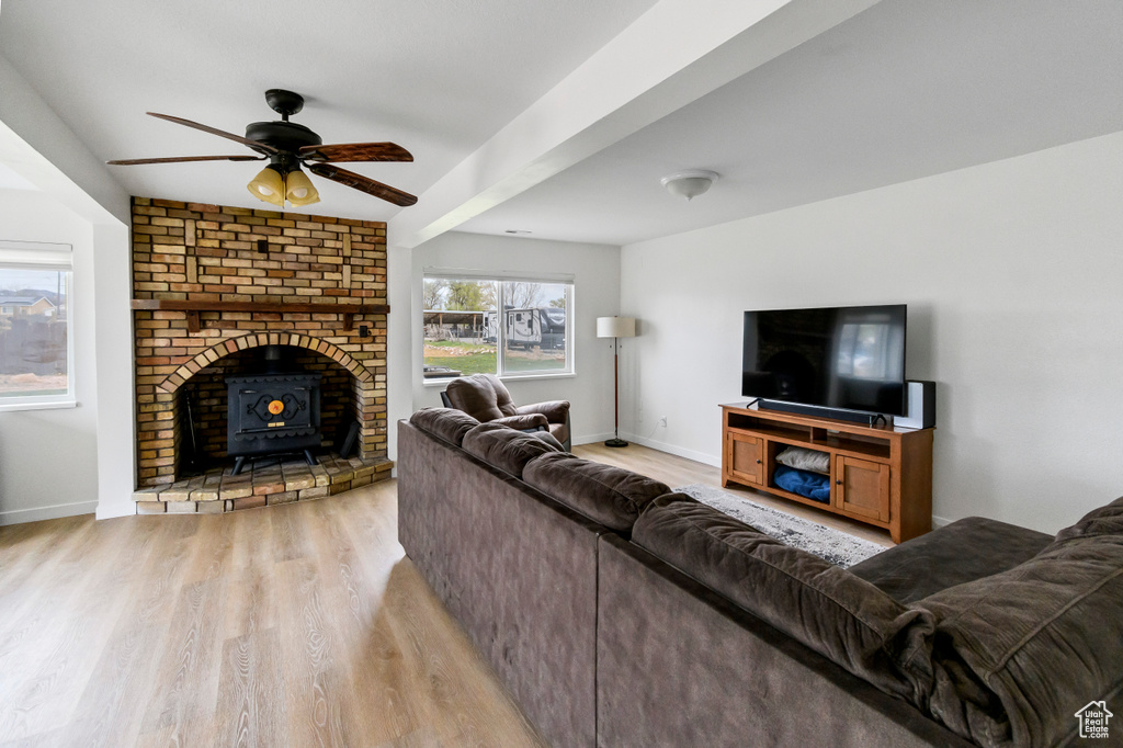Living area featuring a wood stove, a ceiling fan, baseboards, and light wood finished floors