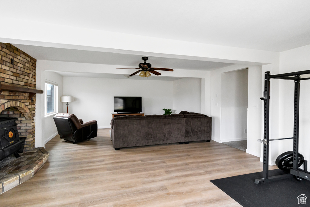 Interior space with baseboards, a ceiling fan, a wood stove, and light wood finished floors