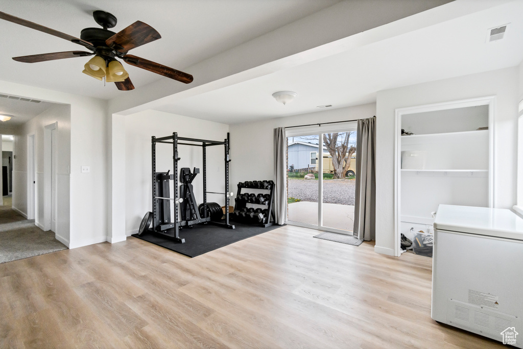 Workout room with a ceiling fan, baseboards, visible vents, and light wood finished floors