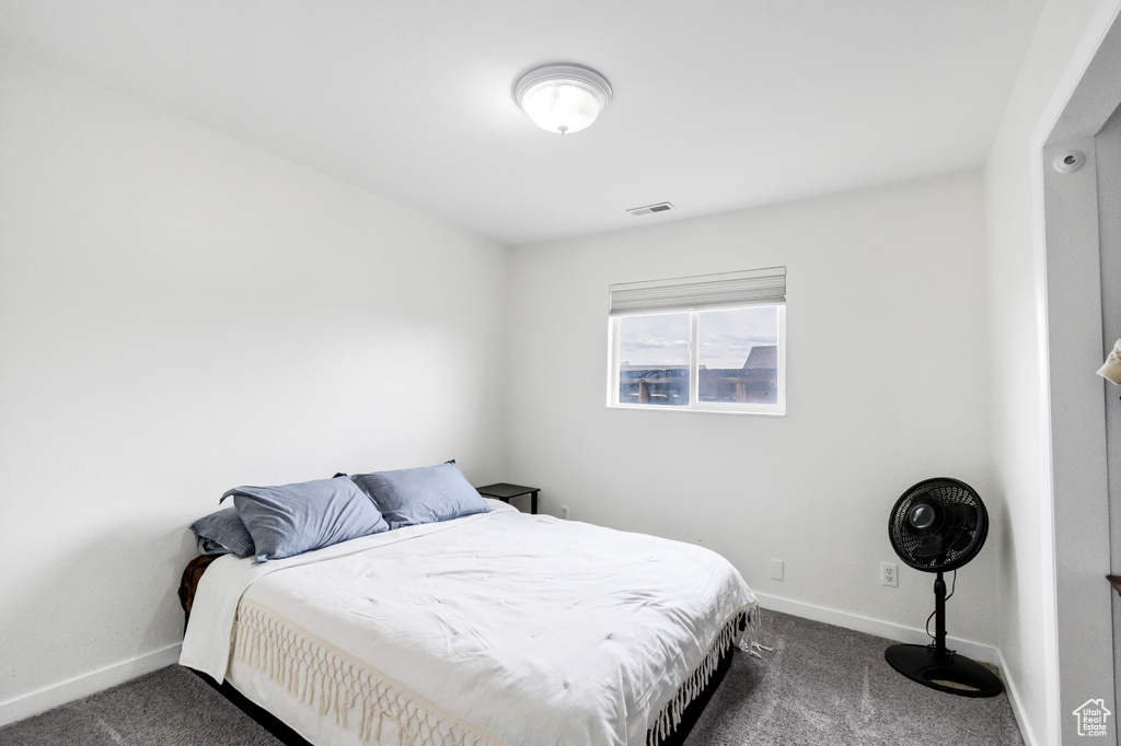 Bedroom featuring baseboards, dark colored carpet, and visible vents