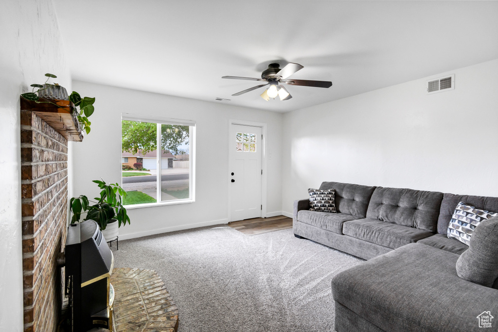 Carpeted living area featuring a ceiling fan, baseboards, and visible vents