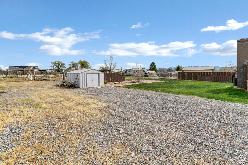 View of yard featuring a shed, an outbuilding, and fence