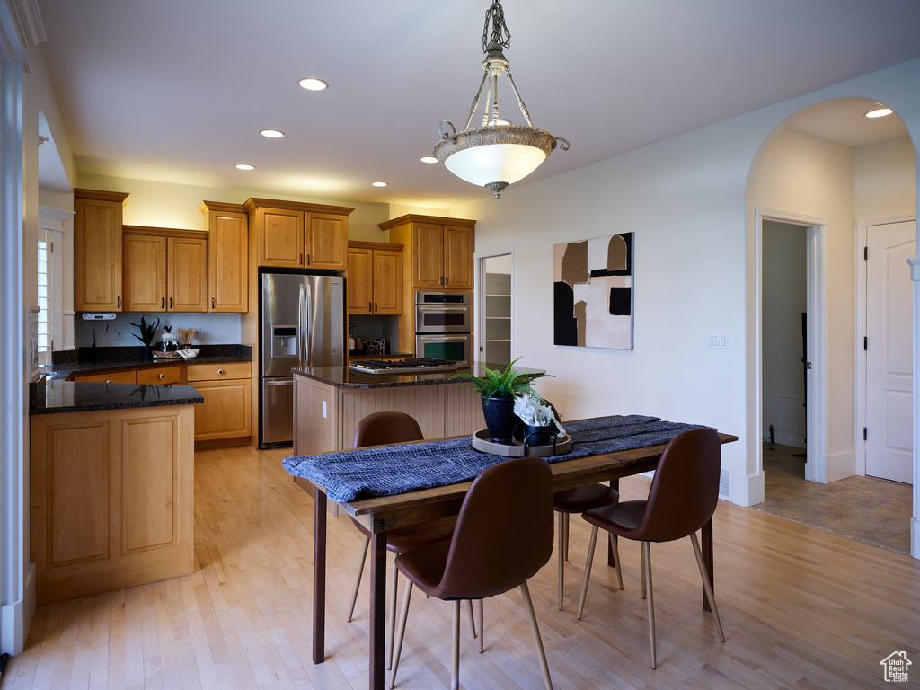 Dining space with recessed lighting, arched walkways, and light wood finished floors