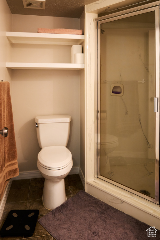 Bathroom with baseboards, a stall shower, and toilet