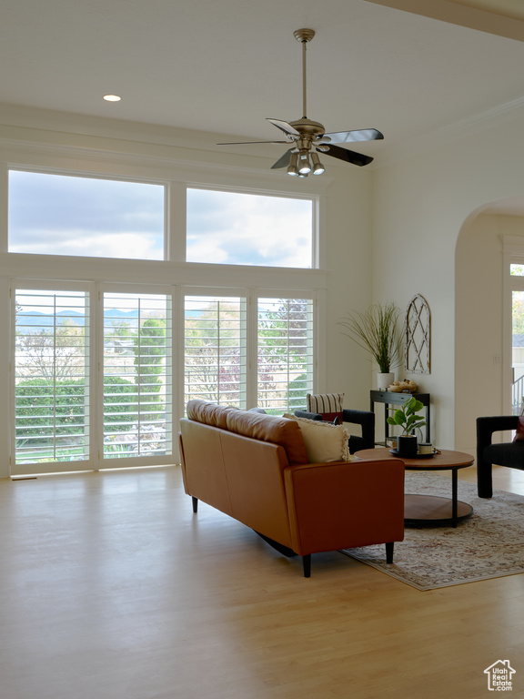 Living room with crown molding, wood finished floors, ceiling fan, recessed lighting, and arched walkways