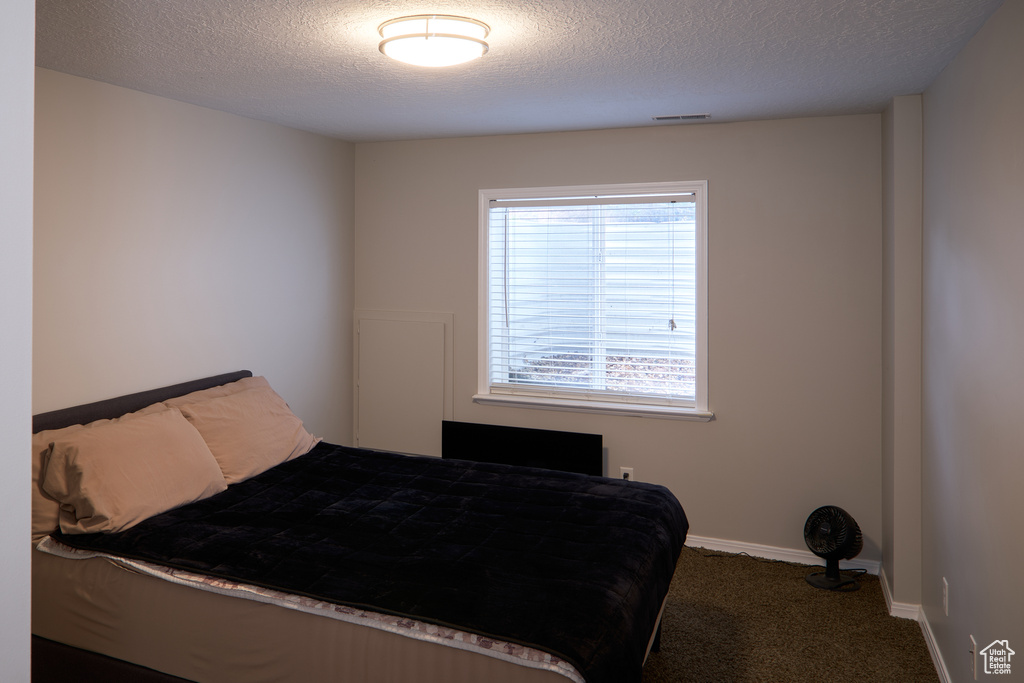 Bedroom with baseboards, carpet flooring, a textured ceiling, and visible vents