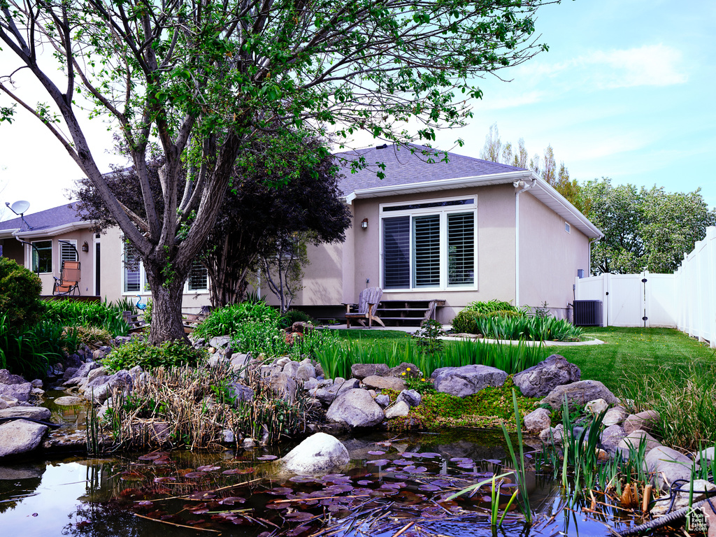 Rear view of house with a lawn, fence, a gate, and a garden pond