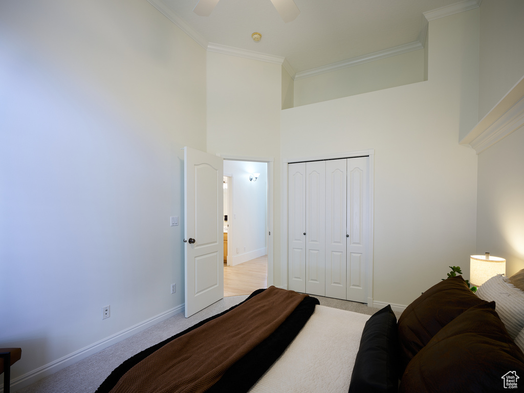Bedroom featuring a closet, ornamental molding, light carpet, and a towering ceiling