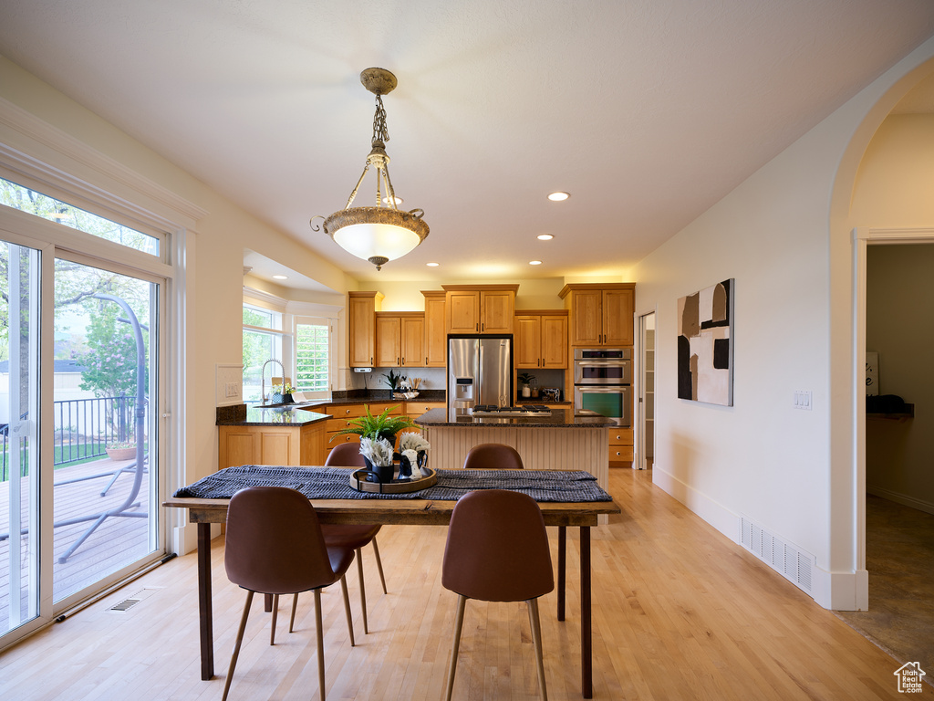 Dining space with recessed lighting, arched walkways, visible vents, and light wood-type flooring