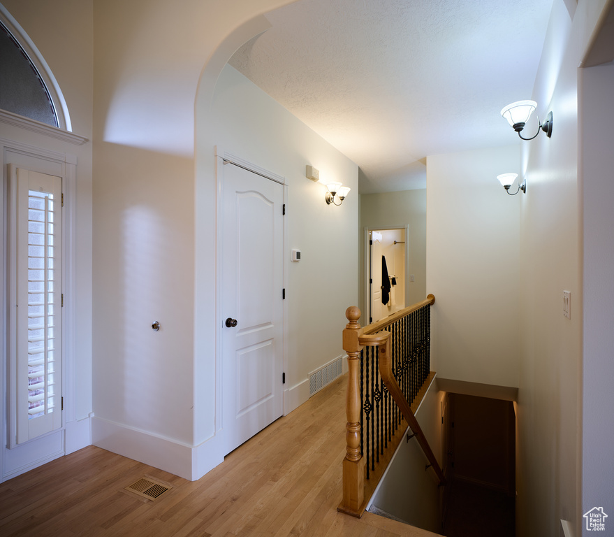 Interior space featuring baseboards, visible vents, light wood-style flooring, and an upstairs landing