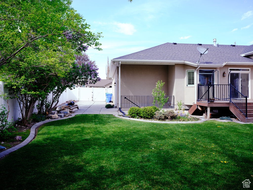 Back of house featuring a fenced backyard, stucco siding, a lawn, and a shingled roof