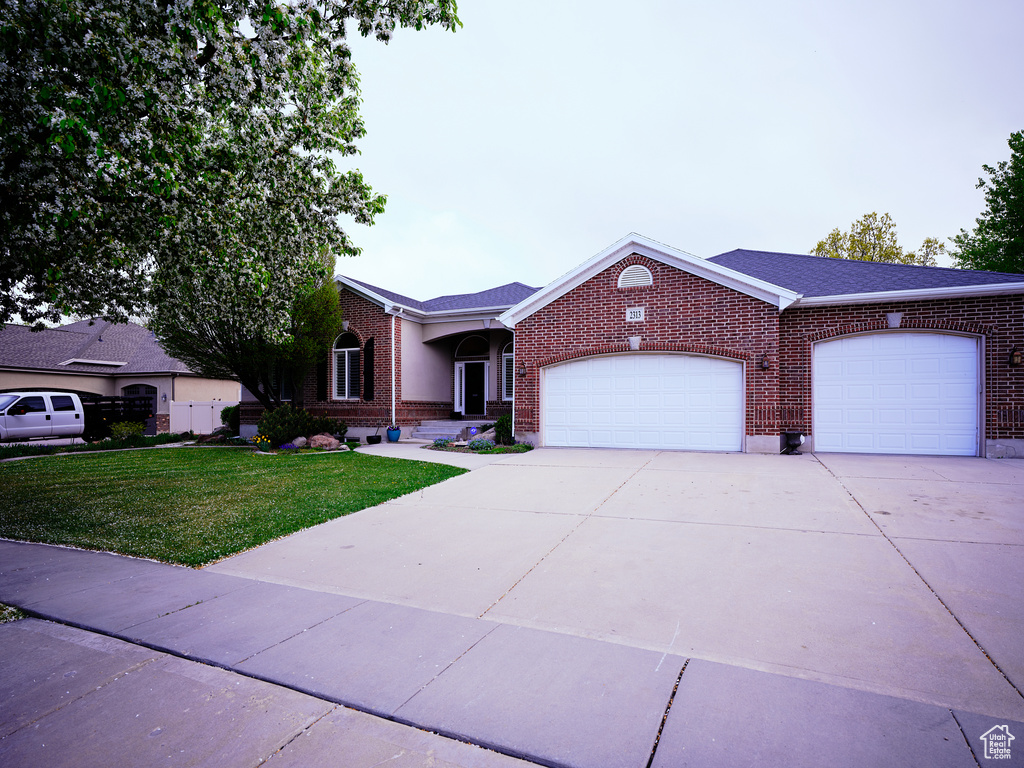 Single story home with concrete driveway, brick siding, an attached garage, and a front yard