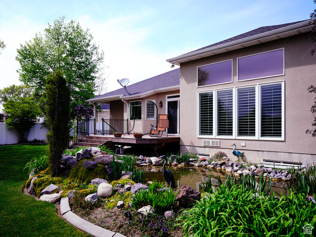 Back of property with a yard, a wooden deck, and stucco siding