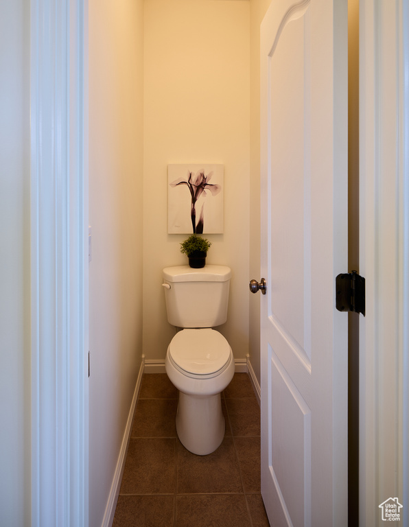 Bathroom featuring toilet, tile patterned floors, and baseboards