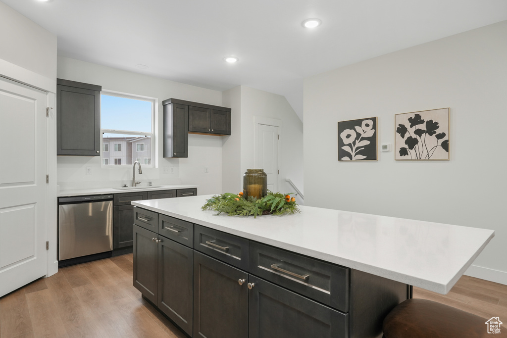 Kitchen with stainless steel dishwasher, a sink, light wood-type flooring, recessed lighting, and light countertops