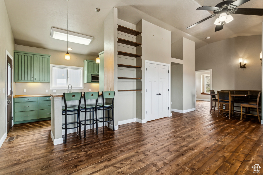 Kitchen with baseboards, dark wood-style floors, stainless steel microwave, a ceiling fan, and green cabinets