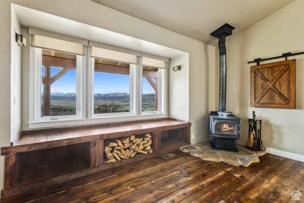 Room details with baseboards, a wood stove, and wood finished floors