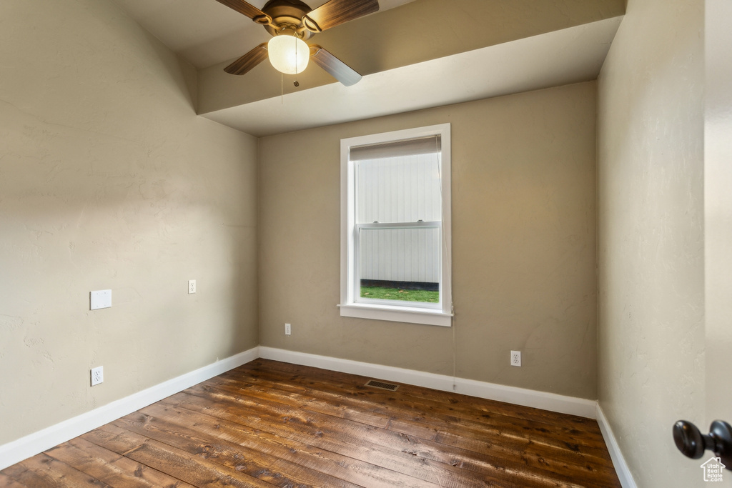 Spare room featuring baseboards, dark wood-style flooring, and a ceiling fan