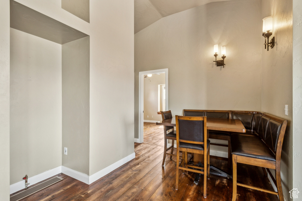 Dining area with baseboards, high vaulted ceiling, and wood finished floors