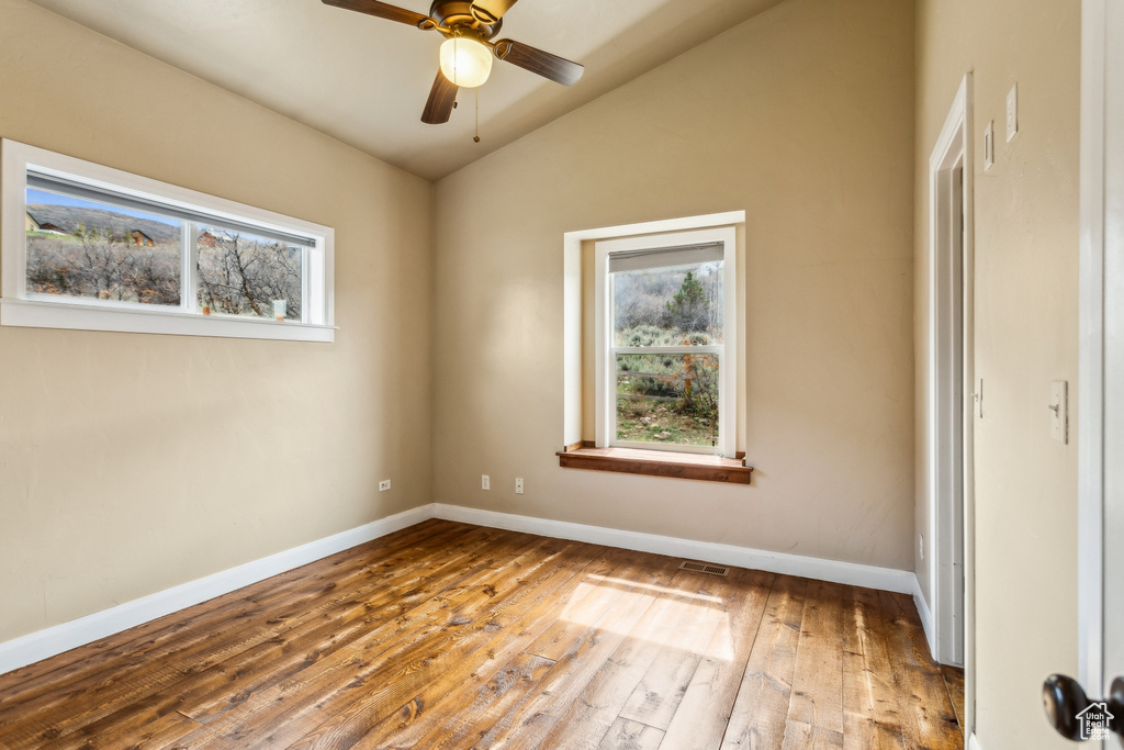 Unfurnished room with plenty of natural light, vaulted ceiling, hardwood / wood-style floors, and visible vents